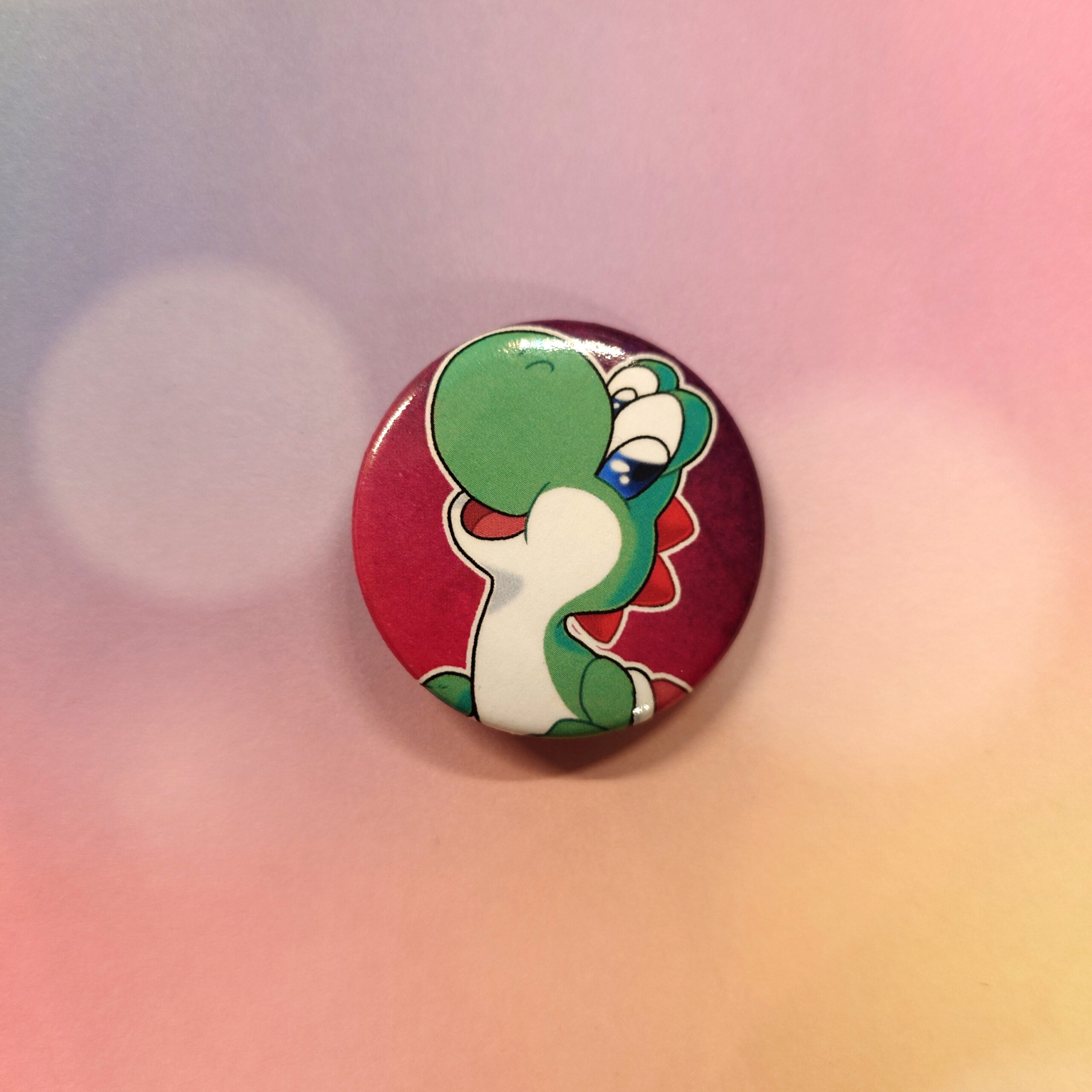 A pin-back button with the drawing of a green dinosaur