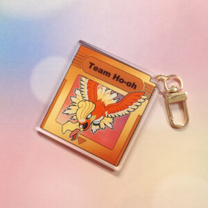 A gold colored game cartridge keychain, retro themed with a character coming out of it